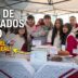 Jóvenes estudiantes de Merlo sonriendo en su stand de la Plaza de Egresados en el Parque de la Unidad Nacional, juntando fondos para su viaje de fin de curso.